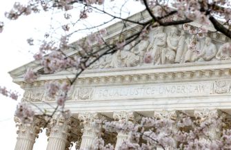 The Supreme Court building with cherry blossoms in the foreground and the inscription "Equal Justice Under Law" visible.
