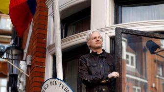 Julian Assange standing at the window of the Ecuadorian Embassy, where he sought asylum for several years.