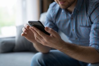 A person holding a smartphone while sitting on a couch.