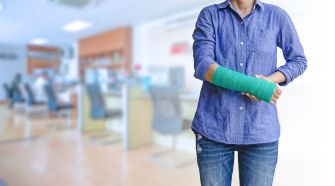 Person with a green cast on their arm, standing indoors in a workplace environment.