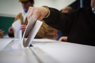 A person casting a ballot into a voting box during an election.