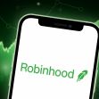 Logo of Robinhood trading app displayed on a smartphone with a green financial graph background. Logo of Robinhood trading app displayed on a smartphone with a green financial graph background.