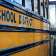 Image of a yellow school bus with the words "SCHOOL DISTRICT" on its side, parked in a school environment. Image of a yellow school bus with the words "SCHOOL DISTRICT" on its side, parked in a school environment.