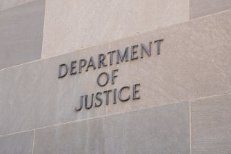Sign on the exterior wall of a building that reads "Department of Justice."