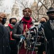 A group of individuals, including a man with a trumpet, speaking at a press conference in front of a building, addressing issues related to a viral incident involving racial profiling. A group of individuals, including a man with a trumpet, speaking at a press conference in front of a building, addressing issues related to a viral incident involving racial profiling.