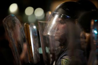 Police officers in riot gear during a nighttime protest.