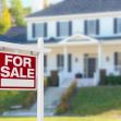 A "For Sale" sign in front of a house with a blurred background. A "For Sale" sign in front of a house with a blurred background.
