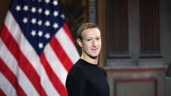 Mark Zuckerberg standing in front of an American flag.