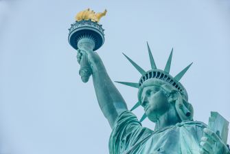 Statue of Liberty holding a torch against a clear sky.