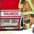 A firefighter standing next to a fire engine with "PARAMEDIC" labeled on the side. A firefighter standing next to a fire engine with "PARAMEDIC" labeled on the side.