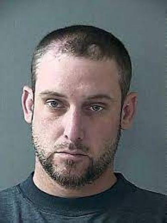 Mugshot of a man with short hair and a beard, looking directly at the camera.