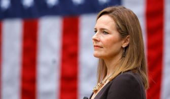 Judge Amy Coney Barrett standing in front of an American flag.