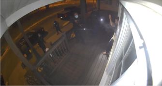 Surveillance footage showing armed bounty hunters and police officers at a home's front porch during a raid.