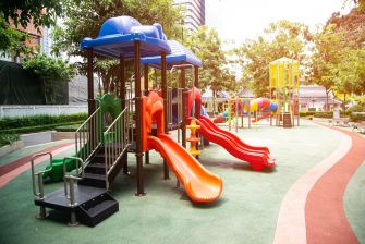 Playground equipment at a daycare facility, with slides and climbing structures surrounded by greenery.