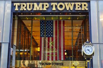 The entrance of Trump Tower in New York City, featuring the American flag and a clock.