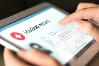 Close-up of a person's hand using a tablet to view a medical record.