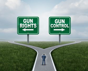 A person standing at a crossroads with signs indicating "Gun Rights" and "Gun Control" on either side.