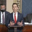 Senator Josh Hawley speaking during the Senate session regarding objections to the election results, with other senators in the background. Senator Josh Hawley speaking during the Senate session regarding objections to the election results, with other senators in the background.
