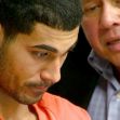 A young man in an orange jumpsuit appears attentive as another individual speaks to him, likely in a courtroom setting. A young man in an orange jumpsuit appears attentive as another individual speaks to him, likely in a courtroom setting.