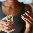 A person inspecting a jar of cannabis buds. A person inspecting a jar of cannabis buds.