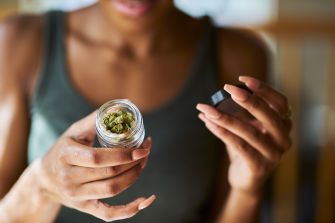 A person inspecting a jar of cannabis buds.