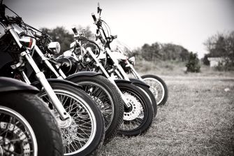 Row of motorcycles parked outdoors, showing the front tires and detailing.