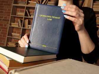 A person holding a book titled "Landlord-Tenant Law" among other books on a table.