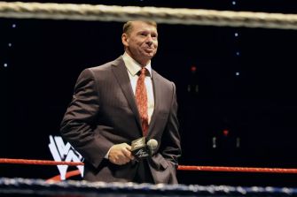 Vince McMahon speaking in a wrestling ring during a WWE event.