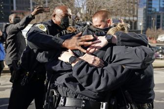 A group of police officers embracing one another in solidarity after the Nashville bombing incident.