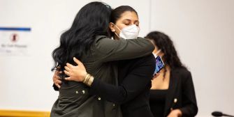 Two women embrace in a courtroom setting, celebrating after a verdict in a case involving press freedom.