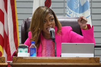 Mayor Tiffany Henyard speaking at a village board meeting, gesturing while addressing concerns over her administration.