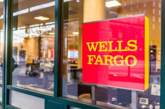 Wells Fargo bank sign displayed at a branch location, with the interior visible through the glass window.