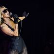 Miley Cyrus performing on stage with a microphone. Miley Cyrus performing on stage with a microphone.