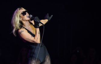 Miley Cyrus performing on stage with a microphone.