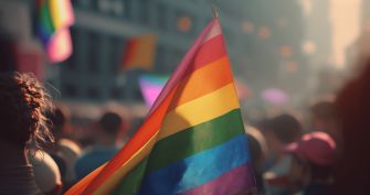 A crowd holding a rainbow flag during a celebration or protest in support of LGBTQ rights.