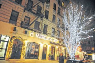 Exterior view of Mamajuana Cafe, a restaurant located in New York City, adorned with holiday lights.