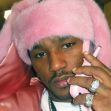 Cam’ron wearing a fuzzy pink coat and hat, holding a pink flip phone. Cam’ron wearing a fuzzy pink coat and hat, holding a pink flip phone.