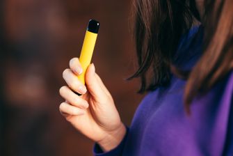 A person holding a yellow e-cigarette device.
