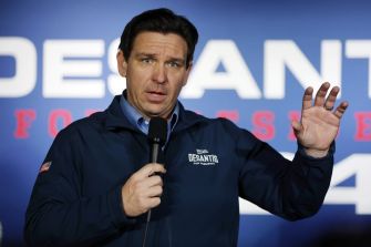 Governor Ron DeSantis speaking at an event, with a microphone in hand and gesturing.