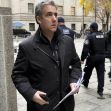 Michael Cohen walking outside a courthouse, holding documents, with security personnel in the background. Michael Cohen walking outside a courthouse, holding documents, with security personnel in the background.