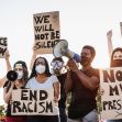 A diverse group of protesters holding signs with messages about justice, racism, and political dissent, while some use megaphones to amplify their voices. A diverse group of protesters holding signs with messages about justice, racism, and political dissent, while some use megaphones to amplify their voices.