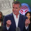 California Governor Gavin Newsom speaking passionately at a press conference, with a backdrop of supportive figures. California Governor Gavin Newsom speaking passionately at a press conference, with a backdrop of supportive figures.