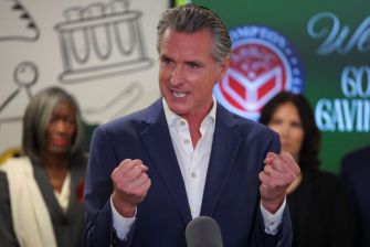 California Governor Gavin Newsom speaking passionately at a press conference, with a backdrop of supportive figures.