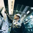 A worker inspecting electrical control panels in an industrial setting. A worker inspecting electrical control panels in an industrial setting.