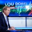 Lou Dobbs sitting at the set of "Lou Dobbs Tonight" with a graphic of the show's title in the background. Lou Dobbs sitting at the set of "Lou Dobbs Tonight" with a graphic of the show's title in the background.
