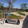 A dock-less electric scooter parked by a bike rack in a public area. A dock-less electric scooter parked by a bike rack in a public area.