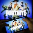 A person holding a smartphone showing the game "Fortnite," with the game's logo and characters displayed on the screen. A person holding a smartphone showing the game "Fortnite," with the game's logo and characters displayed on the screen.