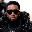 Sean "Diddy" Combs wearing sunglasses and a detailed black outfit adorned with roses, looking serious amidst a blurred background. Sean "Diddy" Combs wearing sunglasses and a detailed black outfit adorned with roses, looking serious amidst a blurred background.