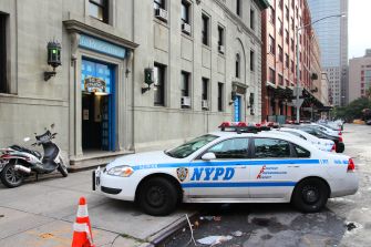 Image of an NYPD police car parked outside a police station on a city street.