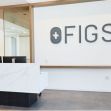 Modern office reception area with the Figs logo prominently displayed. Modern office reception area with the Figs logo prominently displayed.